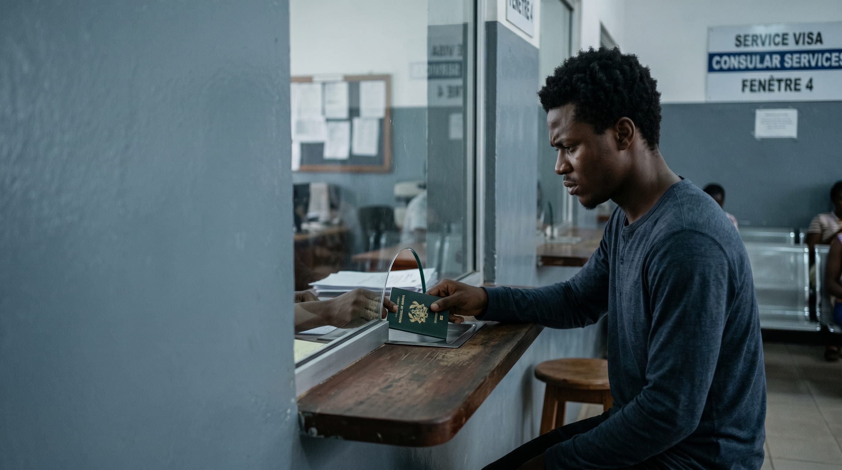 A visa applicant slides his passport across the consular window